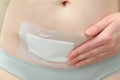 Closeup of woman belly with a scar from a cesarean section with a medical bandage on blue background Royalty Free Stock Photo