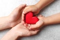 Closeup of woman and child holding heart on grey stone background. Donation concept Royalty Free Stock Photo