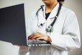 Closeup of a woman doctor wearing white medical gown and blue gloves, stethoscope. Female nurse holding a laptop in her hands. Royalty Free Stock Photo