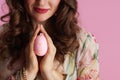 Closeup on woman with easter egg praying against pink background