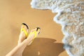 Closeup of woman with flip flops on sand near sea. Beach accessories Royalty Free Stock Photo