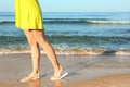 Closeup of woman with flip flops on sand near sea. Beach accessories Royalty Free Stock Photo