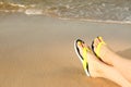 Closeup of woman with flip flops on sand near sea. Beach accessories Royalty Free Stock Photo