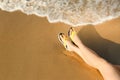 Closeup of woman with flip flops on sand, space for text. Beach accessories Royalty Free Stock Photo