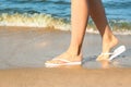 Closeup of woman with flip flops on sand, space for text. Beach accessories Royalty Free Stock Photo