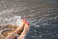 Closeup of woman with flip  on sand near sea, space for text. Beach accessories Royalty Free Stock Photo
