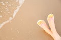 Closeup of woman with  flip flops on sand near sea, space for text. Beach accessories Royalty Free Stock Photo
