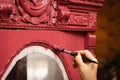 Closeup of woman hand aging carved ornaments of massive wooden cupboard door in pink color. Giving new life to old stuff