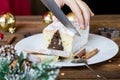 Woman hand cut christmas chocolate cake with holiday decoration. Food xmas background. Royalty Free Stock Photo