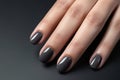 Closeup woman hand with dark gray and black nail polish on fingernails. Nail manicure with gel polish at luxury beauty salon.