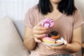 Woman hand eating donuts , sugar addiction concept , unhealthy eating sweet food