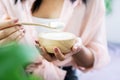 Closeup woman hand eating yogurt hand holding wooden spoon and bowl of yogurts Royalty Free Stock Photo