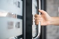 Closeup woman hand holding the door bar to open the door with glass reflection background Royalty Free Stock Photo