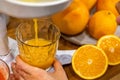 Closeup woman hand holding glass under flow of detox healthy orange juice use citrus press Royalty Free Stock Photo