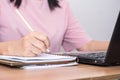 Closeup a woman hand holding pencil and using a laptop computer working at her desk in the office. A businesswoman is writing down Royalty Free Stock Photo