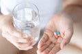 Closeup woman hand holding pills and glass of water, health care and medical concept, selective focus Royalty Free Stock Photo