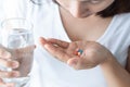 Closeup woman hand holding pills and glass of water, health care and medical concept, selective focus Royalty Free Stock Photo