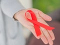 Closeup woman hand holding red ribbon HIV Royalty Free Stock Photo