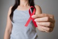 Closeup woman hand holding red ribbon HIV, world AIDS day awareness ribbon. Healthcare and medicine concept Royalty Free Stock Photo