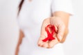 Closeup woman hand holding red ribbon HIV, world AIDS day awareness ribbon. Healthcare and medicine concept Royalty Free Stock Photo