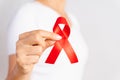 Closeup woman hand holding red ribbon HIV, world AIDS day awareness ribbon. Healthcare and medicine concept Royalty Free Stock Photo