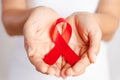 Closeup woman hand holding red ribbon HIV, world AIDS day awareness ribbon. Healthcare and medicine concept Royalty Free Stock Photo