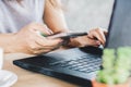 Woman hand holding smart phone and pen writing on notebook with laptop on desk Royalty Free Stock Photo