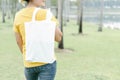 Closeup woman hand holding white bag canvas fabric on green nature background, Save the world concept Royalty Free Stock Photo