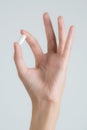 Closeup woman hand holding white pills- on white background. Royalty Free Stock Photo