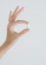 Closeup woman hand holding white pills- on white background.