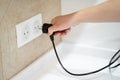 Close up Woman hand insert or pull out elecrticity plug in outlet on the wall