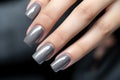 Closeup woman hand with metallic color nail polish on fingernails. Silver nail manicure with gel polish at luxury beauty salon. Royalty Free Stock Photo