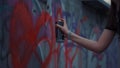 Woman hand painting graffiti on street wall. Girl drawing red heart on building Royalty Free Stock Photo