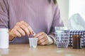 Woman hand preparing to take medicine with glass of water and bottle of pill on desk