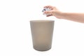 Closeup woman hand throwing paper in brown trash bin.