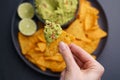Closeup of woman hand with tortilla chips or nachos with fresh tasty guacamole dip Royalty Free Stock Photo