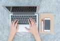 Closeup woman hand typing on keyboard at the gray notebook computer on concrete desk textured background under day light in the