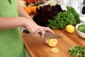 Closeup of woman hands cooking vegetables salad in kitchen. Housewife cuts lemon. Healthy meal and vegetarian concept. Royalty Free Stock Photo