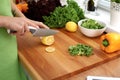 Closeup of woman hands cooking vegetables salad in kitchen. Housewife cuts lemon. Healthy meal and vegetarian concept. Royalty Free Stock Photo