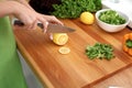 Closeup of woman hands cooking vegetables salad in kitchen. Housewife cuts lemon. Healthy meal and vegetarian concept. Royalty Free Stock Photo