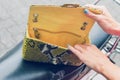 Closeup woman hands with fashion luxury snakeskin python handbag on a retro motorbike background. Outdoors, Bali island.