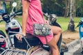 Closeup woman hands with fashion luxury snakeskin python handbag on a retro motorbike background. Outdoors, Bali island.