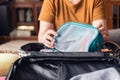 Closeup woman hands holding mesh cosmetic bag and try to put them in luggage. Packing to go on a getaway vacation Royalty Free Stock Photo