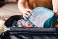 Closeup woman hands holding mesh cosmetic bag and try to put them in luggage. Packing to go on a getaway vacation Royalty Free Stock Photo