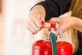 Closeup woman hands with red nailpolish showing how to operate fire extinguisher Royalty Free Stock Photo