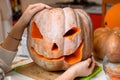 Closeup on woman hands using knife to carve big orange pumpkin Jack-O-Lantern for Halloween party Royalty Free Stock Photo