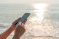 Closeup of woman hands using mobile phone at the beach in sunny day. Business, technology, travel and lifestyle concept Royalty Free Stock Photo