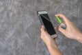 Closeup woman hands using spray alcohol sanitizer cleaning screen smartphone, to prevent the virus and bacterias. Clean smartphone