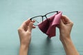 Closeup of woman hands who clean eyeglasses against green table Royalty Free Stock Photo