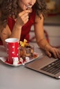 Closeup on woman having christmas cookies and usign laptop Royalty Free Stock Photo